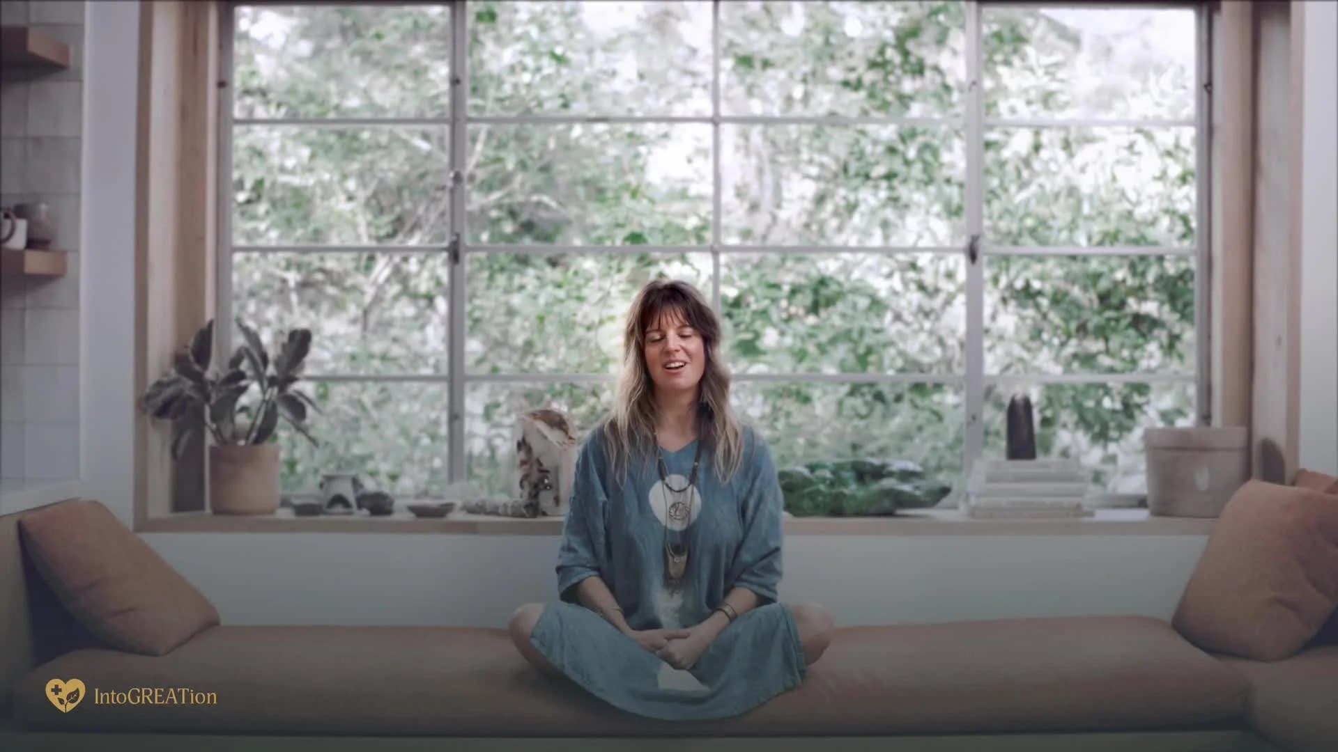 A woman sitting in meditation in a bright window seat